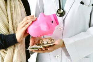 Health insurance concept, Patient paying doctor for medical service with money dollar banknote, Medical cost expense saving in piggy bank.