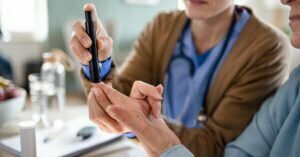 caregiver healthcare worker measuring blood glucose at home