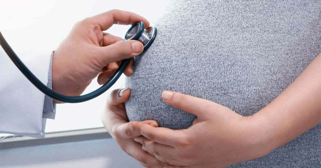 doctor using a stethoscope while examining a pregnant woman