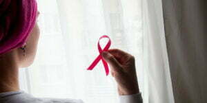 woman with breast cancer holding pink ribbon