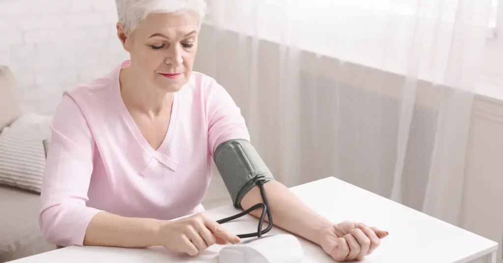 senior woman taking her blood pressure to monitor hypertension crisis