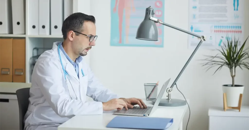 doctor using laptop for remote physiological monitoring
