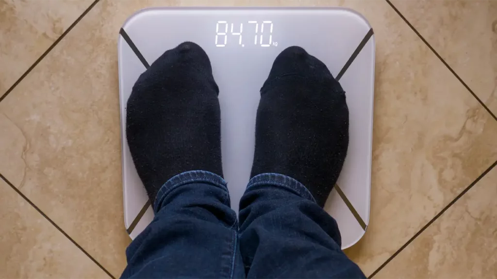 man weighs himself on a weighing scale