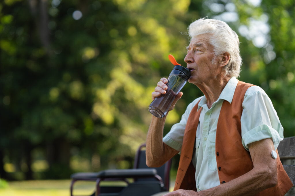 Senior man drinking water outdoor to better manage his diabetes